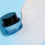 belif Moisturizing Eye Bomb 25ml - Eye cream with peptides, bakuchiol & caffeine against wrinkles & dark circles. Image image white cream swirl on blue background. 