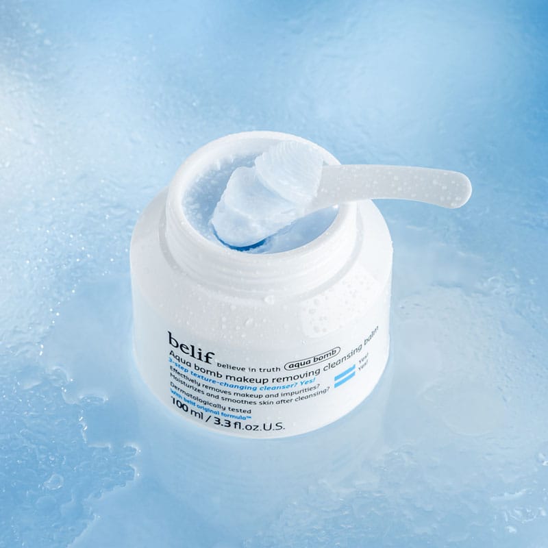 belif Cleansing Balm 100ml – Feuchtigkeitsspendender Abschminkbalsam mit Lotusblume & Vitamin E. Imagebild mit Applikator, ohne Deckel auf blauem Hintergrund.