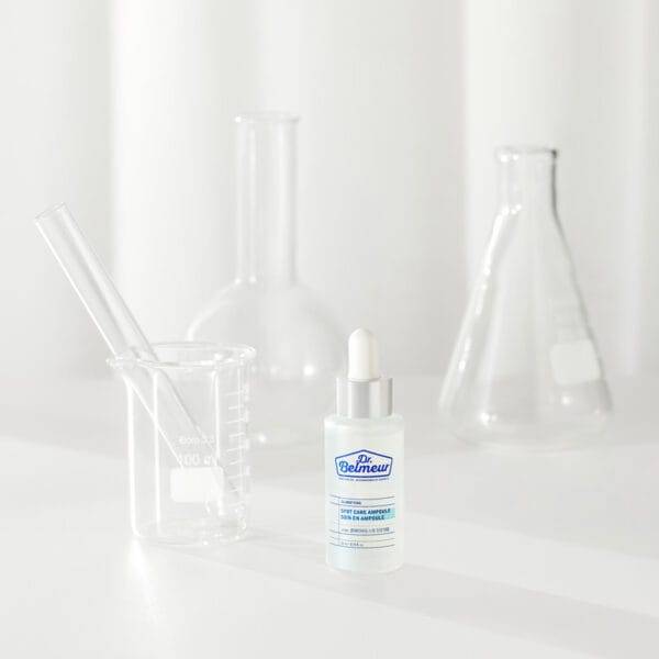 Dr. Belmeur Spot Care Ampoule 22ml – beruhigendes Serum mit Panthenol, Beta-Glucan, Chaga-Pilz und Teebaumöl gegen Unreinheiten und Rötungen. Abbildung Produkt mit Reagenzgläser im Hintergrund.