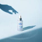 Dr. Belmeur Spot Care Ampoule 22ml – beruhigendes Serum mit Panthenol, Beta-Glucan, Chaga-Pilz und Teebaumöl gegen Unreinheiten und Rötungen. Abbildung Hand greift nach dem Serum.