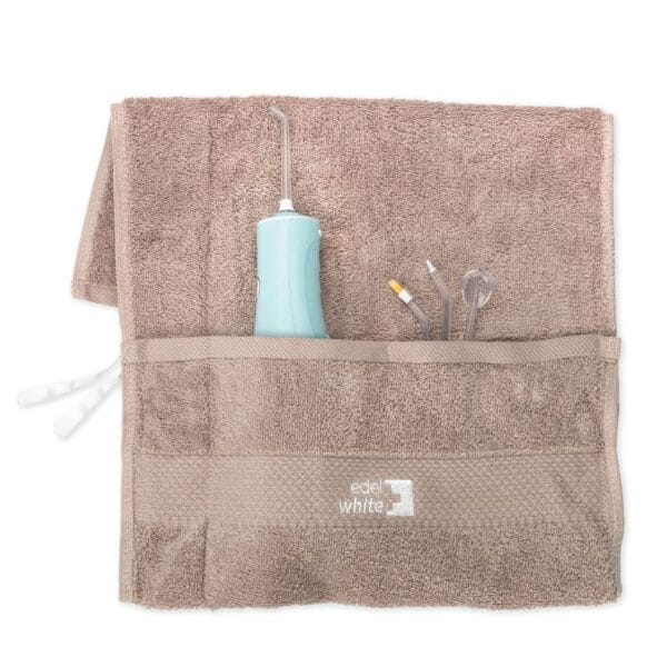 edel+white Flosserpik Power Spa – Der Champion der mobilen Mundduschen mit viel Power. Abbildung Produkt im Handtuch mit verschiedenen Aufsätzen.