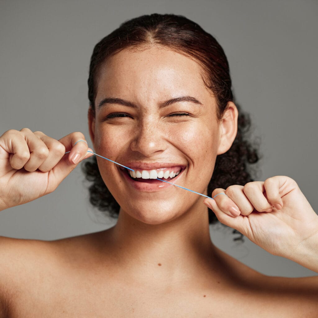 Lachende Frau mit dunklen Haaren benutzt edel+white Zahseide – für gesunde, gepflegte Zähne und Zahnfleisch